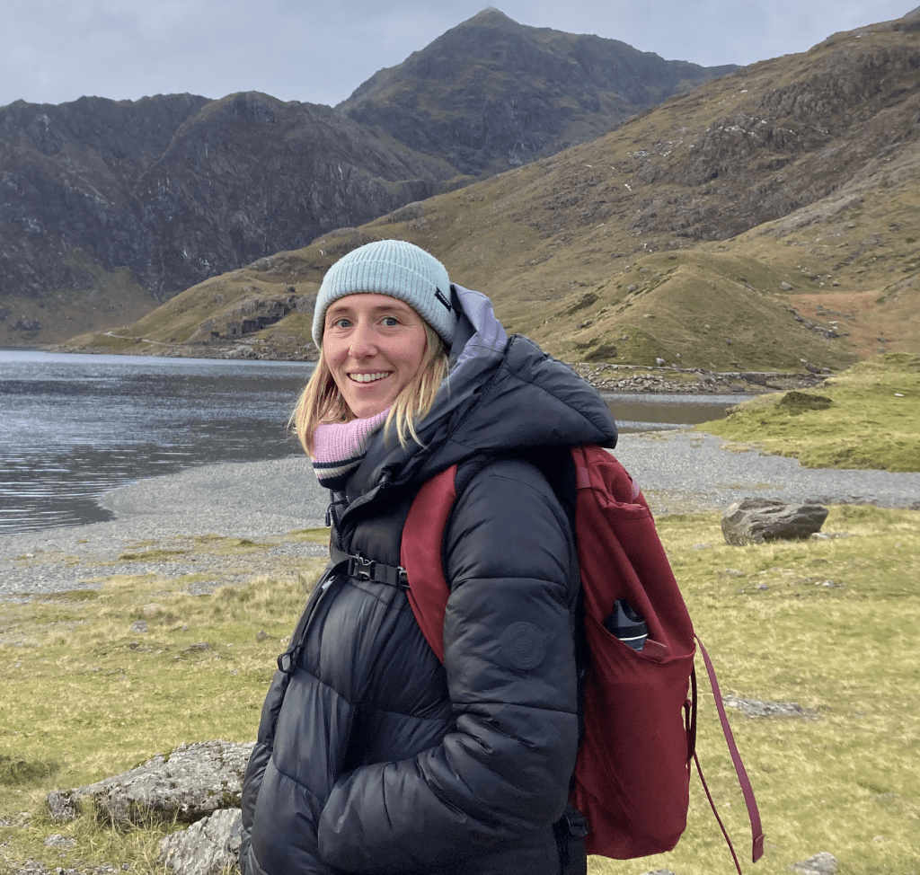 A person smiling for a photo with a mountain in the background.